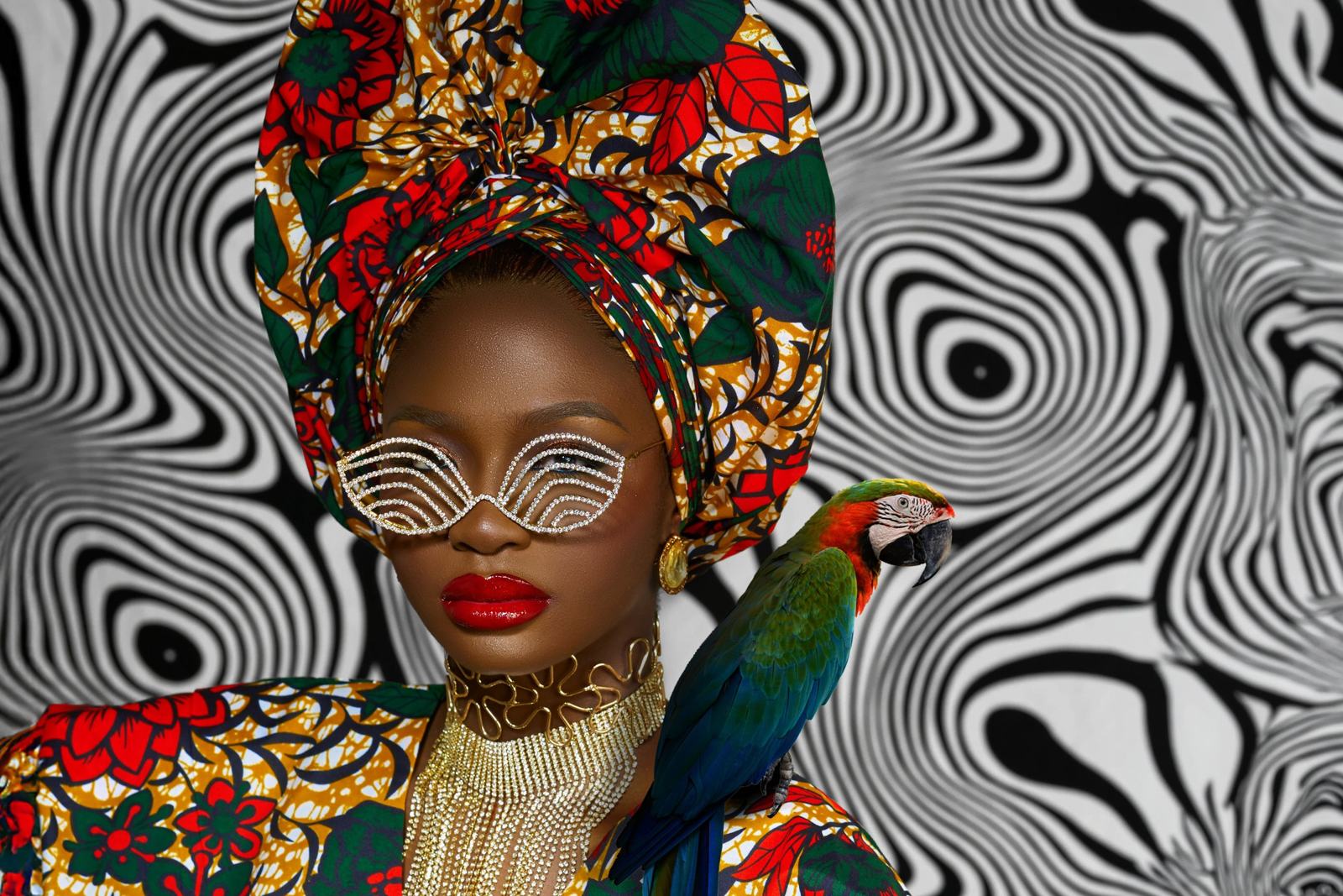Woman in patterned headwrap and sculptural glasses against an op-art backdrop
